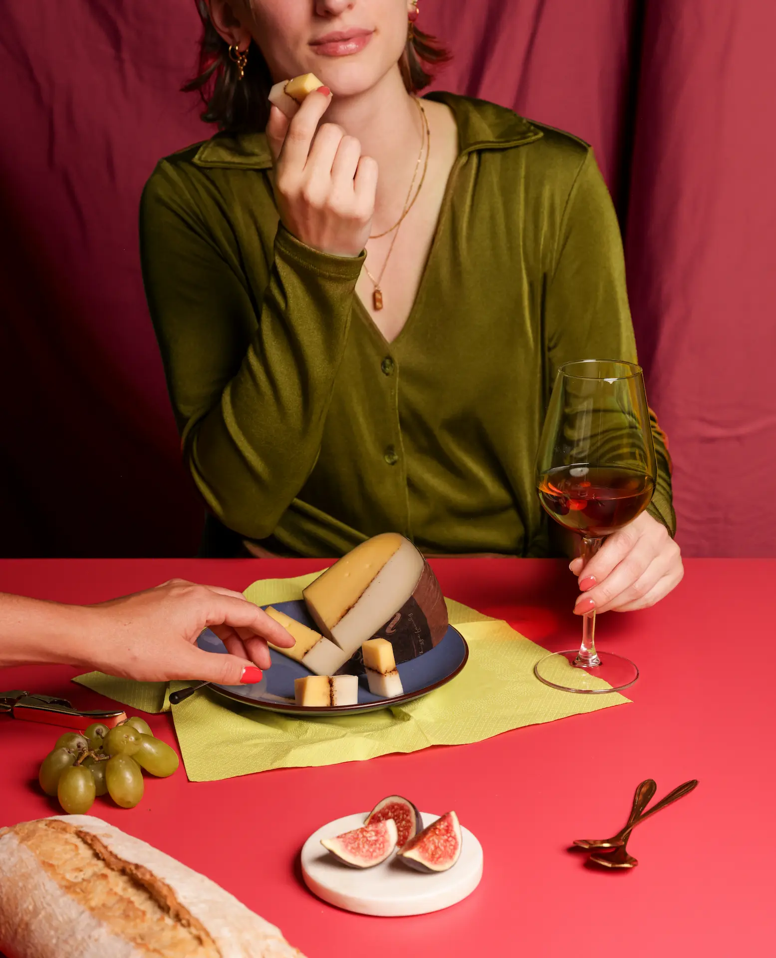 Tafel vol kaas met brood, cocktail glas en groente en fruit. Vrouw aan het lunchen